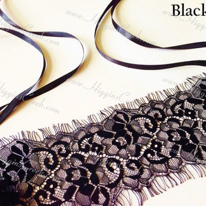May include: Black lace trim with a scalloped edge and frayed edges. The lace has a floral pattern.