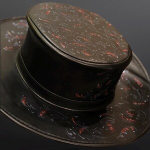 May include: A black leather top hat with a wide brim and intricate red and white floral designs.