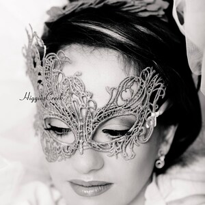 Puede incluir: Una fotograf&iacute;a en blanco y negro de una mujer que lleva una m&aacute;scara de encaje delicada e intrincada. La m&aacute;scara es plateada y tiene un dise&ntilde;o de mariposa. El texto "For Children & Small Faces" es visible en la parte inferior de la imagen.