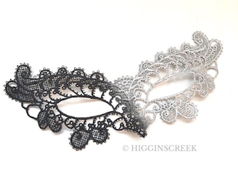 May include: A black and silver lace masquerade mask with a delicate design. The mask is half black and half silver, with a gradient effect.