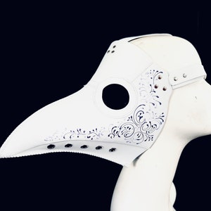 Puede incluir: M&aacute;scara blanca de m&eacute;dico de la peste con un dise&ntilde;o floral detallado y agujeros para los ojos. La m&aacute;scara est&aacute; hecha de cuero y tiene un pico largo.