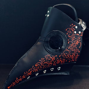 May include: A black leather plague doctor mask with red floral detailing and silver rivets.