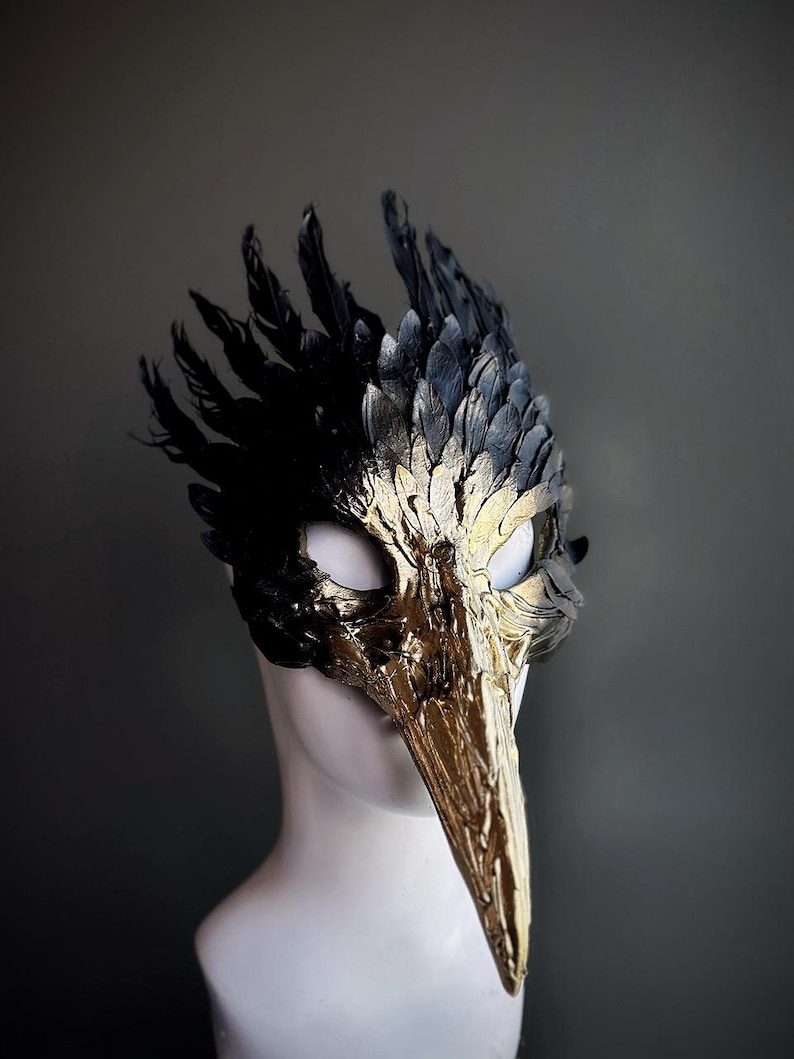Black and gold bird skull masquerade mask with a long beak and feathers.
