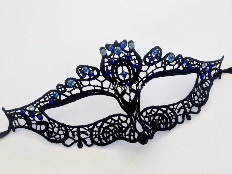 May include: Black lace masquerade mask with blue rhinestones. The mask has a delicate design and is perfect for a costume party or a night out.