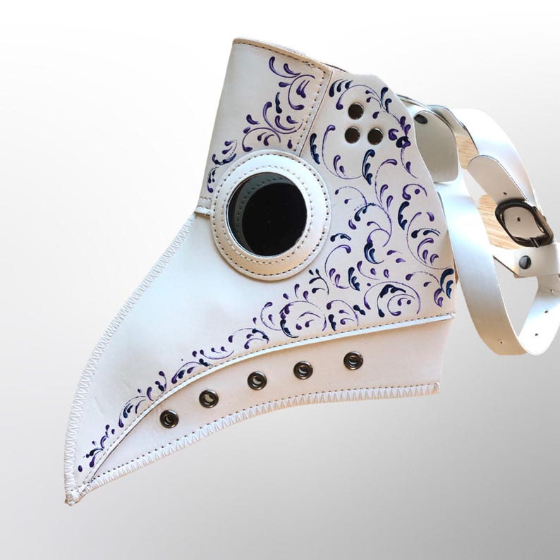May include: White leather plague doctor mask with a purple floral design and a black eye piece. The mask has a long beak and is secured with straps.