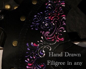 May include: Close-up of a black leather surface with a hand-drawn filigree design in shades of purple, pink, and white. The text "Hand Drawn Filigree in any color(s)" is visible below the design.