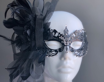 May include: Black masquerade mask with rhinestones and a black feather and ribbon embellishment.