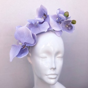 May include: A lavender orchid headband with five flowers. The headband is made of a thin, flexible material and is designed to fit comfortably on the head.