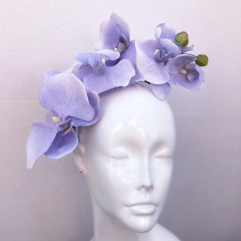 May include: A lavender orchid headband with five flowers. The headband is made of a thin, flexible material and is designed to fit comfortably on the head.