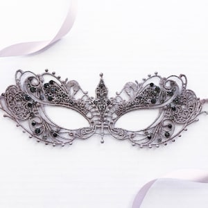 May include: A delicate, gray lace masquerade mask with black rhinestones. The mask has a delicate, intricate design and is perfect for a masquerade ball or costume party.