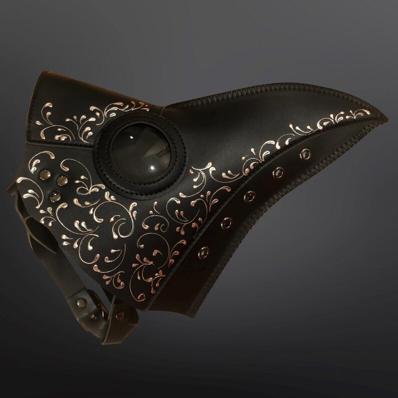 May include: A black leather plague doctor mask with a gold floral design and a clear eye piece.
