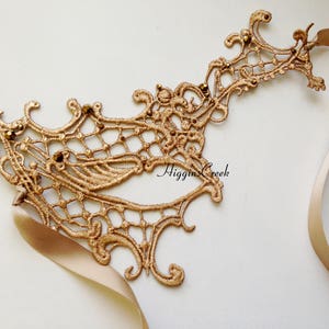 May include: Gold lace masquerade mask with a delicate, intricate design and a satin ribbon tie.