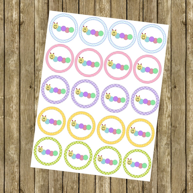 May include: A sheet of 20 round cupcake toppers featuring a smiling caterpillar with a yellow face and multi-colored body. The toppers are printed on white paper with a variety of colorful borders.