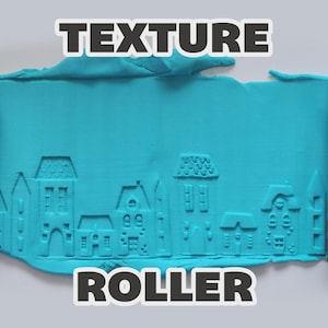 May include: A brown cylindrical texture roller with a carved house pattern, shown pressing into a flat sheet of bright turquoise modeling clay. The clay displays a detailed embossed cityscape design featuring various building shapes and rooflines.