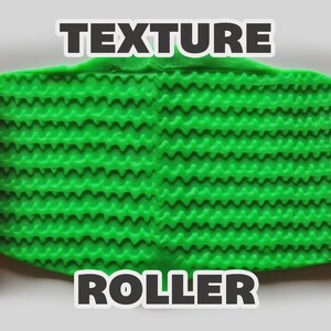 May include: Two orange cylindrical texture rollers with a repeating zigzag pattern positioned on either side of a flat, bright green rectangular piece of clay that has been imprinted with the same horizontal zigzag texture. The text TEXTURE ROLLER is visible.