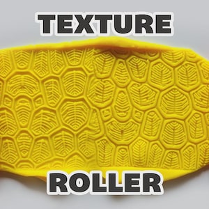 May include: Two orange cylindrical texture rollers with a repeating geometric leaf-like pattern flanking a central yellow slab of clay. The clay displays a deep, embossed impression of the same pattern. The text "TEXTURE ROLLER" is visible.