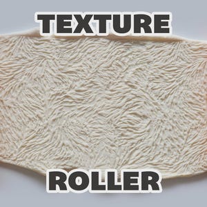May include: An orange texture roller with a raised, intricate, fur-like pattern, shown alongside a white, flat, rectangular piece of material that has been embossed with the same detailed, swirling, hair-like texture. The text TEXTURE ROLLER is visible.