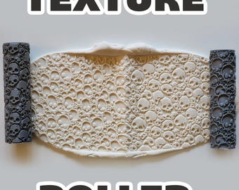 May include: A texture roller with a skull pattern, alongside a clay sheet with the same skull design. The words "TEXTURE" and "ROLLER" are displayed in bold, black text. The rollers are dark gray.