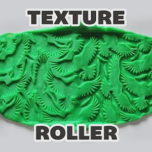 May include: A pink cylindrical texture roller with an engraved pattern of flying birds, shown pressing into a flat piece of bright green modeling clay. The embossed clay displays a repeating design of birds in flight. The text TEXTURE ROLLER is visible.