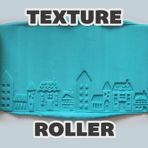 May include: A bright yellow cylindrical texture roller positioned on either side of a flat, rectangular piece of teal modeling clay. The clay is embossed with a detailed cityscape pattern featuring various house designs and building silhouettes.