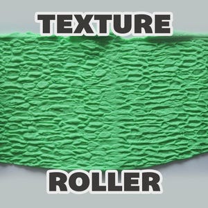 May include: A black cylindrical texture roller with a raised stone pattern, shown pressing into a bright green slab of modeling clay. The text "TEXTURE ROLLER" is printed in bold white letters with a black outline at the top and bottom.