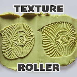 May include: Two magenta cylindrical texture rollers positioned on the sides of a light yellow clay slab. The clay features two embossed ammonite shell patterns created by the rollers. The text "TEXTURE ROLLER" is printed in white letters.