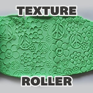 May include: Two dark gray cylindrical texture rollers flanking a sheet of bright green clay. The clay surface is embossed with a repeating pattern of peace signs and smiling flowers. The text "TEXTURE ROLLER" is displayed in bold white letters.