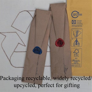 Two bookmarks wrapped in brown kraft paper with wax seals and the back of a delivery envelope showing eco credentials on an upcycling logo.  Stating: Packaging recycle-able, widely recycled, upcycled, perfect for gifting