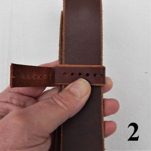 Shown here step 2 of fitting a replacement belt loop strap keeper, shown in a hand.
2. Trim one side to lay across strap.