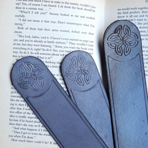3 of the grey, domed top with celtic knot leather bookmarks in organic grey resting on an open book