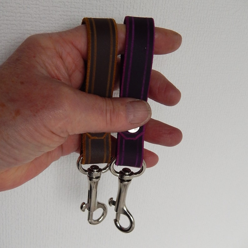 Simple, strong and useful leather loops with a metal spring clip firmly attached.  Use on a belt or strap to hold small items - such as keys, a hand towel, etc - or as a keyring in its own right.  Two shown in a hand