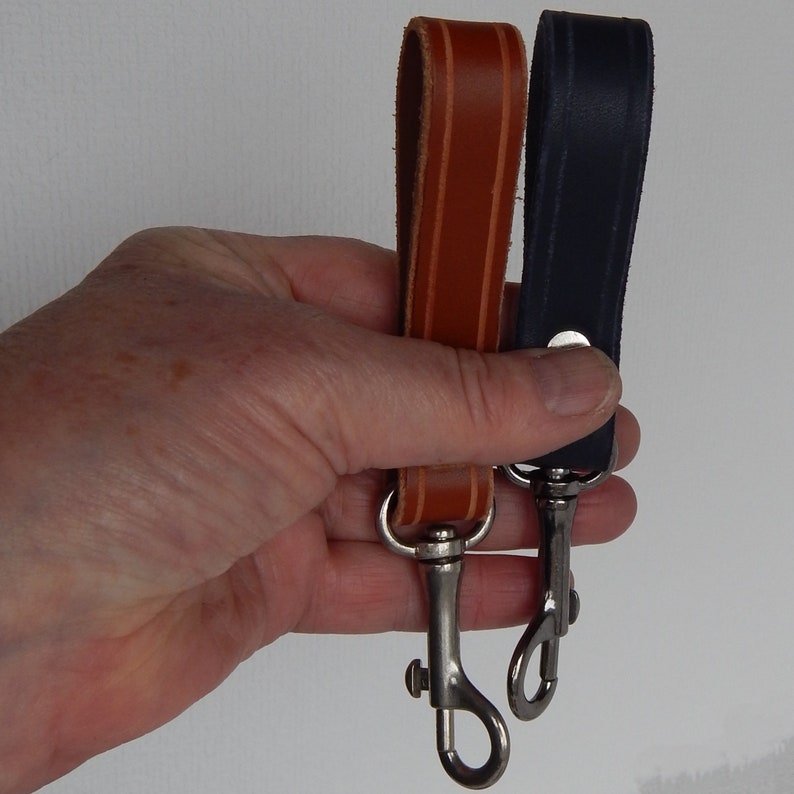 Simple, strong and useful leather loops with a metal spring clip firmly attached.  Use on a belt or strap to hold small items - such as keys, a hand towel, etc - or as a keyring in its own right.  Two shown in a hand