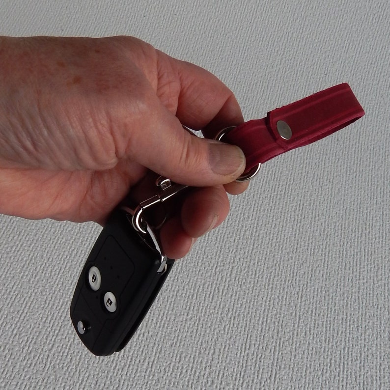 Simple, strong and useful leather loops with a metal spring clip firmly attached.  Use on a belt or strap to hold small items - such as keys, a hand towel, etc - or as a keyring in its own right.  Red shown in a hand with car key