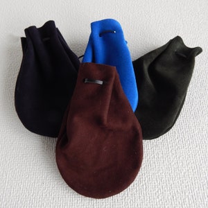 May include: Three drawstring pouches in different colors: dark blue, brown, and dark green. The pouches are made of a soft, textured fabric.