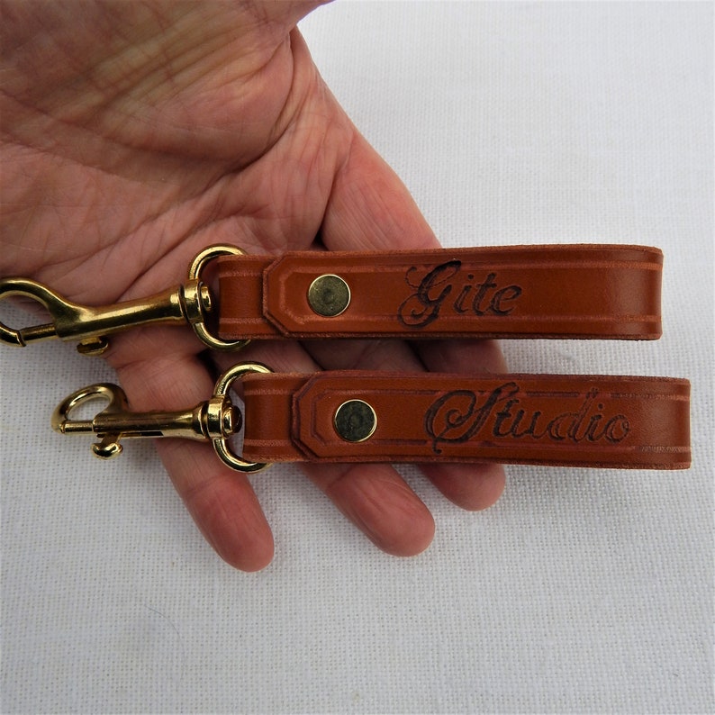 Simple, strong and useful leather loops with a metal spring clip firmly attached.  Use on a belt or strap to hold small items - such as keys, a hand towel, etc - or as a keyring in its own right.  Two shown with optional personalisation