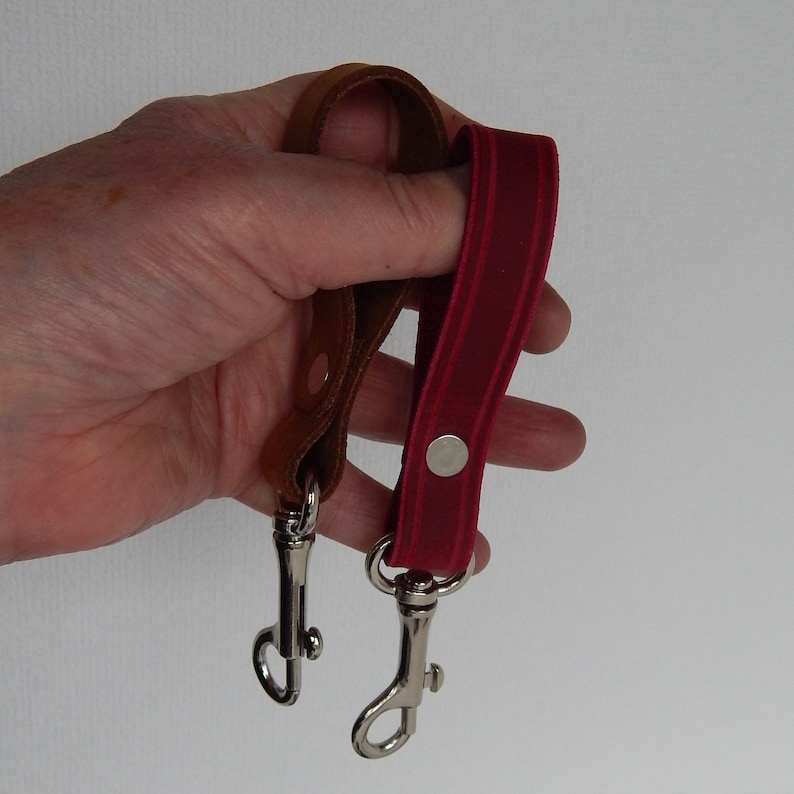 Simple, strong and useful leather loops with a metal spring clip firmly attached.  Use on a belt or strap to hold small items - such as keys, a hand towel, etc - or as a keyring in its own right.  Two shown in a hand