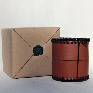 A circular leather pot with another already packed up for dispatch.