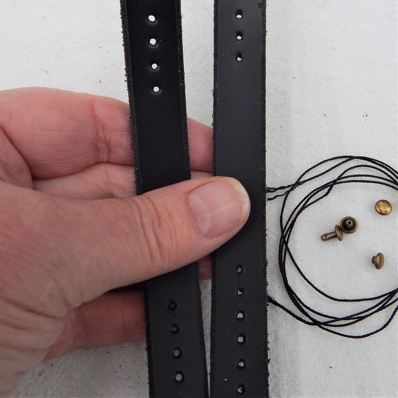 Replacement cut-to-fit belt loops in black leather here shown in a hand.  Shows two strips of leather with prepunched holes and the rivits and thread, either can be used to make the loop.