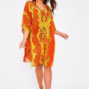 May include: A red and yellow patterned kaftan with a tassel tie at the neckline. The kaftan has a loose fit and is made of a lightweight fabric.
