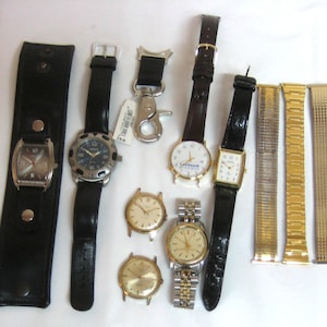 May include: A collection of various wristwatches and watch bands, including several leather straps, gold-tone metal link bracelets, and loose watch faces with round or rectangular dials, some featuring numerical markers and metallic finishes.