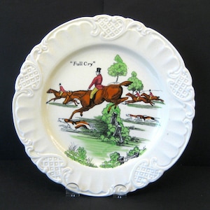 Puede incluir: Plato de cerámica blanco con un borde elevado y una escena de caza. La escena representa a tres jinetes a caballo saltando una valla. El texto "Full Cry" está impreso en el plato.