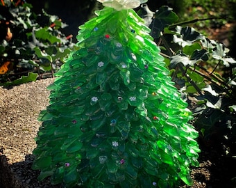 May include: A green glass Christmas tree ornament decorated with white snowflakes and colorful gems. The tree is topped with a white glass star.
