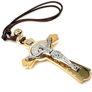 May include: A gold-tone metal crucifix with a silver-tone Jesus figure. The crucifix is attached to a brown cord.