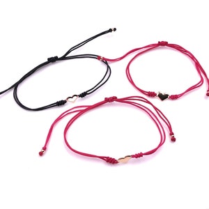 Puede incluir: Tres pulseras ajustables con dijes en forma de corazón. Una pulsera tiene un cordón negro y un corazón dorado. Las otras dos pulseras tienen cordones rojos y corazones dorados. Cada pulsera tiene pequeñas cuentas doradas en los extremos.