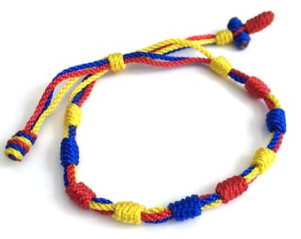 May include: A handmade bracelet featuring a tri-color design of red, yellow, and blue cords. The adjustable bracelet has a sliding knot closure and is made with woven cords. The bracelet is approximately 7 inches in length.