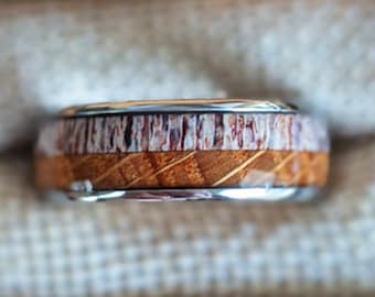 May include: A wooden and stainless steel ring in a wooden box. The ring has a brown wood inlay with a white stripe.