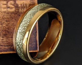 Op de afbeelding: Een gouden trouwring met een getextureerde, lichtgroene afwerking. De ring ligt op een houten oppervlak met de zichtbare tekst "PILLAR STYLES".