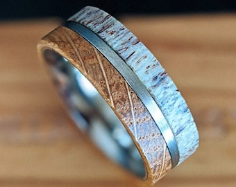 May include: A wedding band with a silver metal band and two wood inlays. One inlay is a light brown wood and the other is a white wood.
