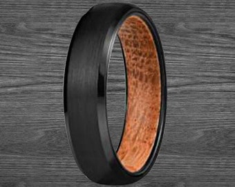 Op de afbeelding: Een zwarte ring van wolfraamcarbide met een bruine houten inlay. De ring heeft een geborstelde afwerking en een afgeschuinde rand.