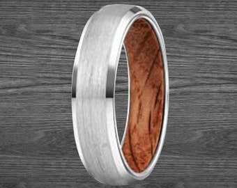 Op de afbeelding: Een zilveren en houten ring met een geborstelde afwerking. De ring heeft een zilveren band met een houten inlay.